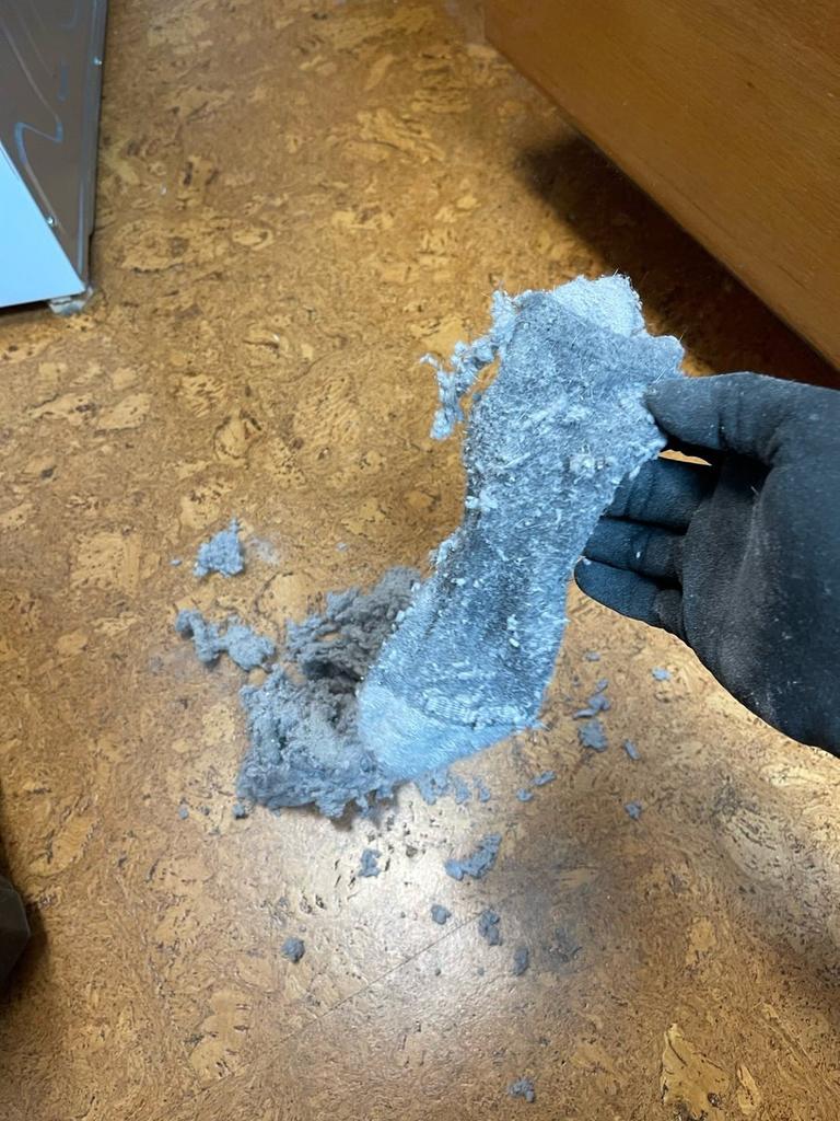 A SwiftPro technician's gloved hand holding a plug of lint pulled out of a Northern Virginia dryer vent