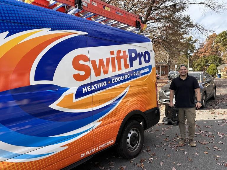 A SwiftPro technician beside a wrapped SwiftPro heating, cooling and plumbing van in Northern Virginia, the van showing Virginia Class A license 2705192276