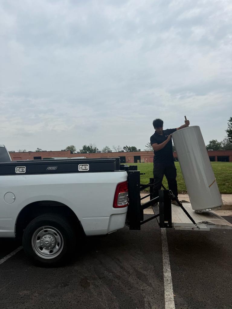 A SwiftPro technician unloading a water heater from a pickup truck liftgate in Northern Virginia